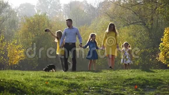 快乐的一家人和他们的小狗在秋天公园散步视频的预览图