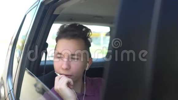 微笑的少年坐在汽车后座打电话视频的预览图