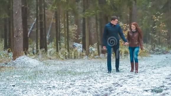 女孩和男人走在秋天雪松森林手牵手慢动作视频的预览图