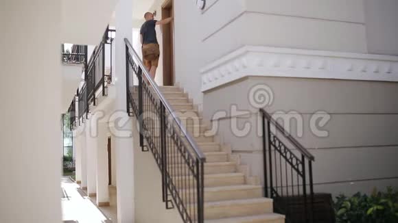 男人拿着包坐在楼梯的台阶上打电话视频的预览图