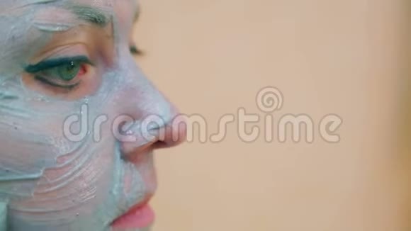 一个微笑的女人的脸头上有一条毛巾皮肤上有一刷蓝色的粘土视频的预览图
