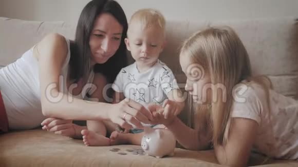 妈妈和两个孩子把钱存到储蓄罐里家庭为未来赚钱投资概念视频的预览图