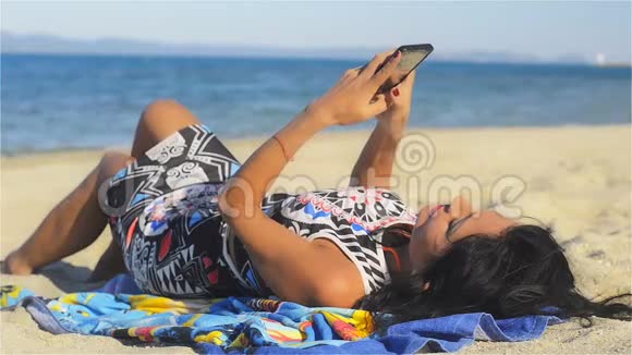 海滩上一个漂亮的黑发女人通过手机聊天娱乐视频的预览图