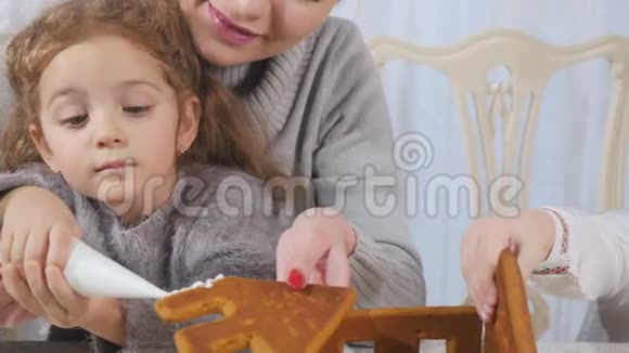 年轻的黑发女人带着小孩做姜饼屋视频的预览图