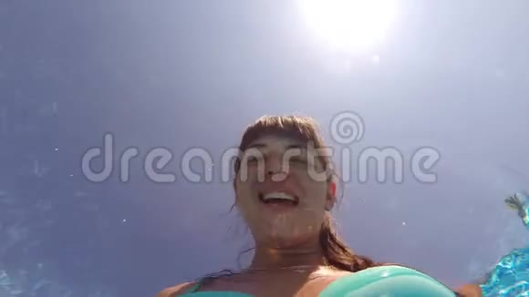 站在游泳池里的年轻微笑女孩做自拍照片相机在她手中的水下关门视频的预览图
