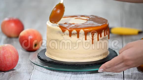 年轻女子把焦糖酱涂在美味的自制蛋糕上带苹果和鲜奶油的美味蛋糕视频的预览图