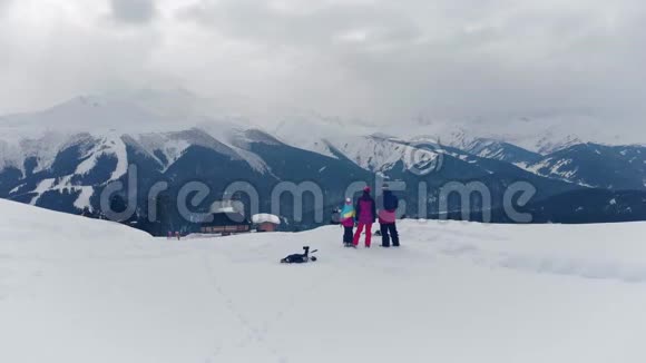 幸福的家庭在山上享受寒假家庭滑雪度假人们观察山景视频的预览图