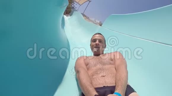 在一个美丽的阳光明媚的日子里年轻快乐的人在水上滑下手里拿着相机的微笑男视频的预览图