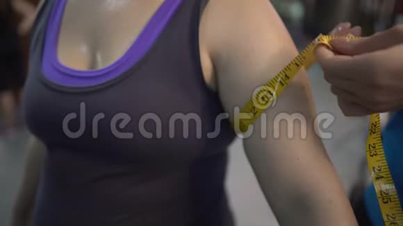 训练员在健身房锻炼后测量女性手臂减肥计划的结果视频的预览图