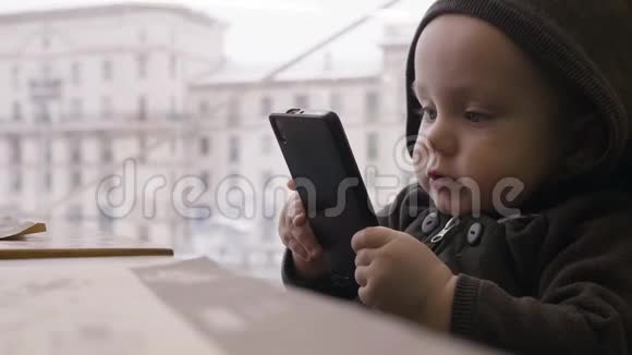 小男孩坐在妈妈腿上桌上玩电话视频的预览图