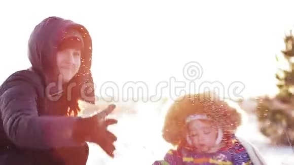 快乐的女人和孩子在夕阳下的冬天公园里玩雪视频的预览图