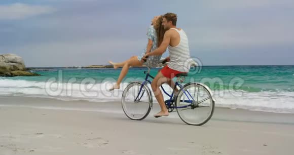 高加索夫妇在海滩上骑自行车的侧面景色视频的预览图