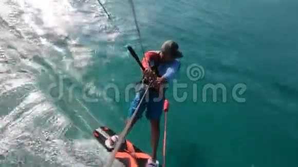 从滑翔在蓝色水面上的风筝冲浪者的风筝吊索上看视频的预览图