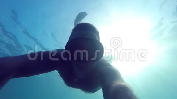 戴着面具在水下游泳的人年轻人潜水手拿相机自画像水下镜头视频的预览图