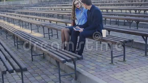 年轻人和商人正坐在公园的长凳上视频的预览图