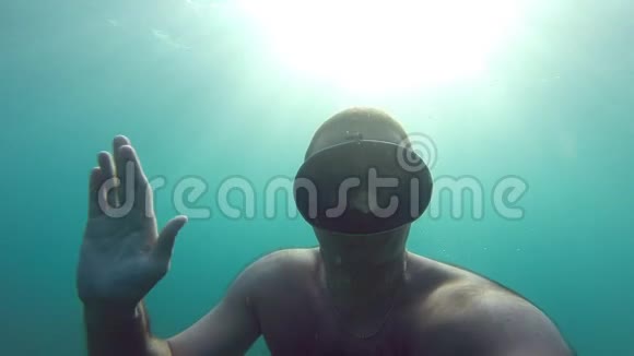 戴着面具在水下游泳的人有人潜水和敬礼相机在手它的自画像水下镜头视频的预览图