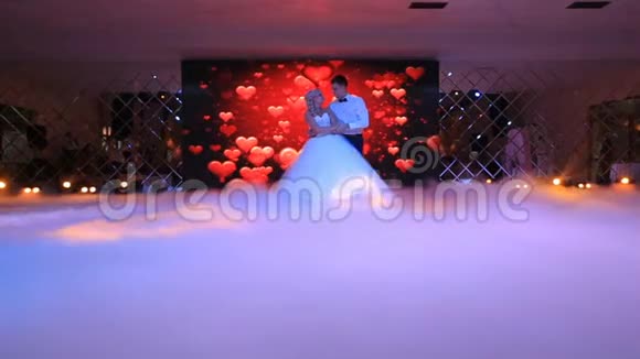 在屏幕的背景下一对新婚夫妇在白色的浓烟中翩翩起舞视频的预览图