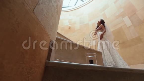 美丽的年轻新娘黑色的长发和时尚的婚纱正在黄色的楼梯上摆姿势观点视频的预览图