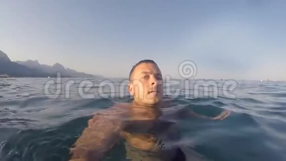 暑假里年轻人从大海里发出问候微笑的家伙游泳和做自画像假日视频的预览图