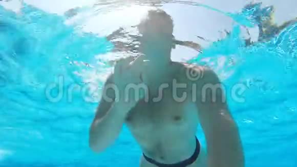 年轻人在游泳池里游泳手里拿着相机水下录像慢动作视频的预览图