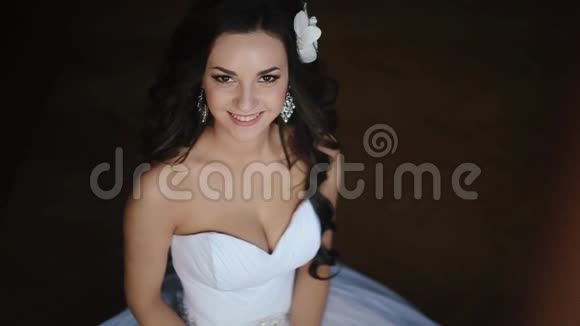 年轻美丽的新娘一头乌黑的卷发上面装饰着兰花和天然的化妆她的笑容可爱视频的预览图