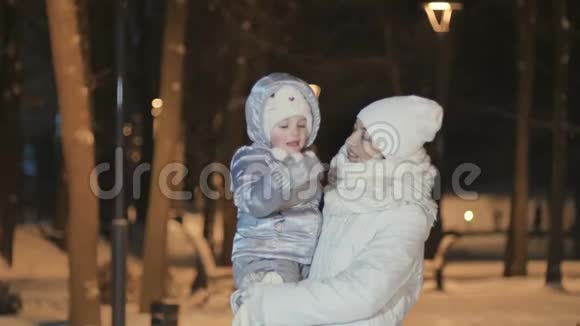 年轻的母亲牵着女儿的手在冬天的公园里和她接吻视频的预览图