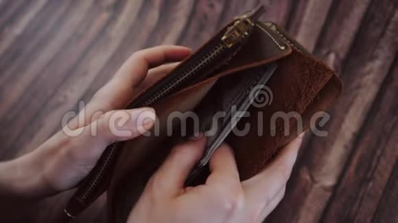 从一个女人的棕色皮夹里取出美元的俯视图女性手拿钱包木制视频的预览图