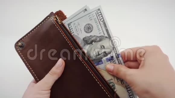 从一个女人的棕色皮夹里取出美元的俯视图女性手拿钱包木制视频的预览图