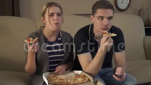 可爱的年轻夫妇坐在沙发上吃披萨视频的预览图