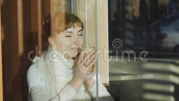 年轻女子在咖啡馆喝咖啡白种人妇女带着蕾丝羊毛围巾欣赏咖啡香气的肖像视频的预览图