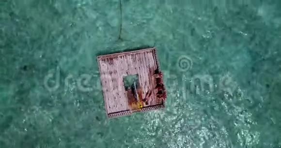 V09224年轻漂亮的女孩在水蓝色清澈的海水中用无人驾驶飞机在浮舟上日光浴视频的预览图
