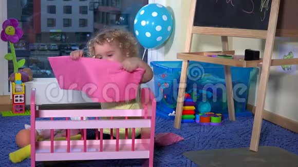 可爱的金发幼儿女孩准备玩具床婴儿床为她的娃娃在家视频的预览图