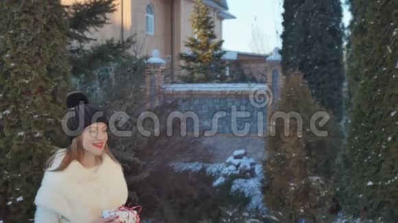 手里拿着圣诞礼物的女孩站在楼梯上的冷杉背景下视频的预览图