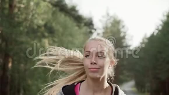清晨一个美丽的年轻女孩沿着红木公路奔跑一个女孩的肖像慢动作视频的预览图