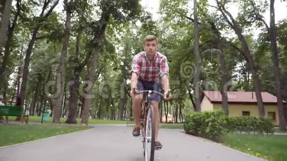 年轻的快乐男子骑着一辆老式自行车在公园路和听音乐运动员在户外骑自行车唱歌视频的预览图