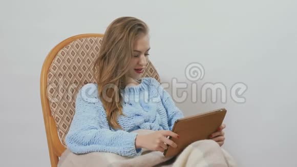 女孩坐在摇椅上裹着毯子用白色背景的平板电脑视频的预览图
