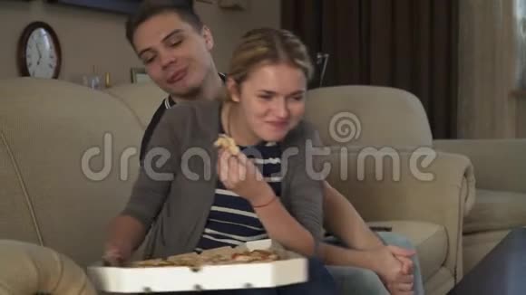可爱的年轻夫妇坐在沙发上吃披萨视频的预览图