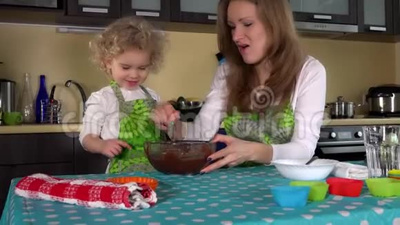 爱玩的妈妈和可爱的小女孩从手指上品尝巧克力面团亲吻视频的预览图