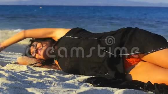 英俊年轻的黑发女人在沙滩上放松视频的预览图