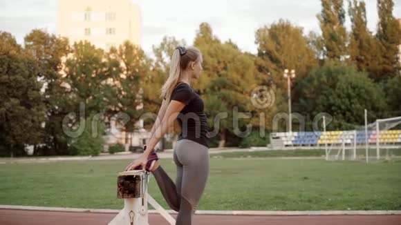 训练前一位跑步的女孩在体育场热身这个女孩蹲在一条腿上视频的预览图