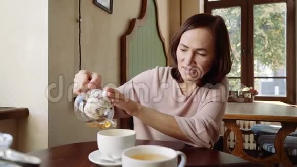 咖啡馆里快乐的女人把茶倒在杯子里视频的预览图