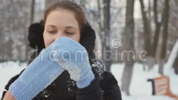 迷人的女人在冬季公园里用冻僵的手吹视频的预览图