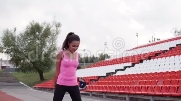 运动员在比赛前在运动场热身那个黑发女孩正在向前倾斜穿粉色衣服的女孩视频的预览图