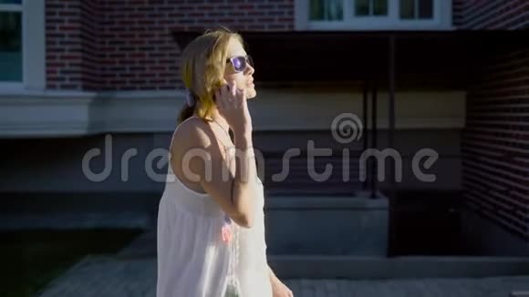 在阳光下年轻的休闲女性走在街上谈论智能手机视频的预览图