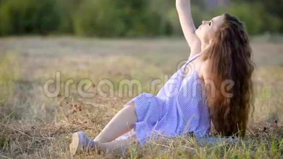 年轻时髦的黑发女郎穿着轻盈的夏装坐在草地上闭着眼睛摆姿势视频的预览图