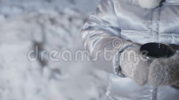 戴手套的小女孩在雪地上拿着一个茶杯视频的预览图