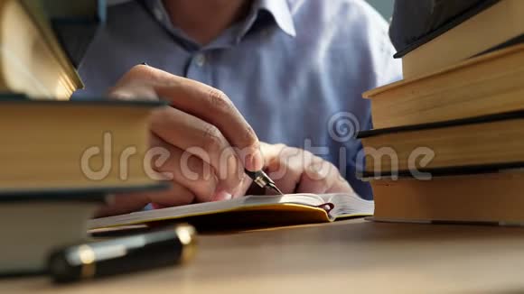 年轻人在一张有成堆的书的桌子上写纸条识和智慧观念视频的预览图