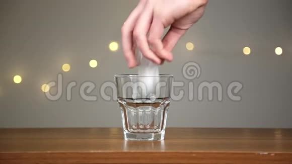 人把冰扔进玻璃杯然后倒椰子水在灯光的背景下视频的预览图
