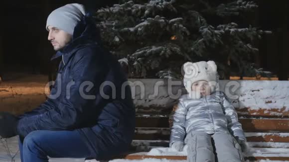 在冬天的公园里争吵的父母和女儿坐在长凳上互相背靠背视频的预览图