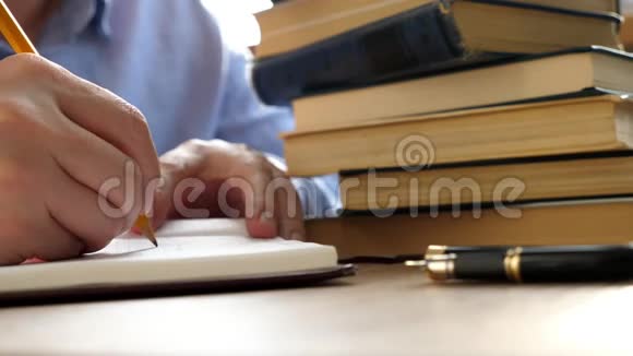 学生正在用一张桌子上放着一堆书的钢笔写作视频的预览图